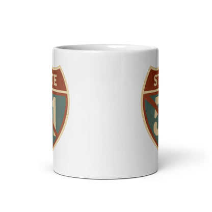 View of white ceramic mug with road sign graphic by State Limit Apparel to both sides.