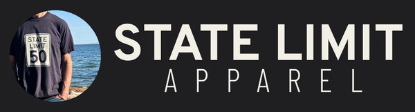 A model on a beach wearing a State Limit 50 bold graphic t-shirt by State Limit Apparel. Blue skies & ocean in the background.